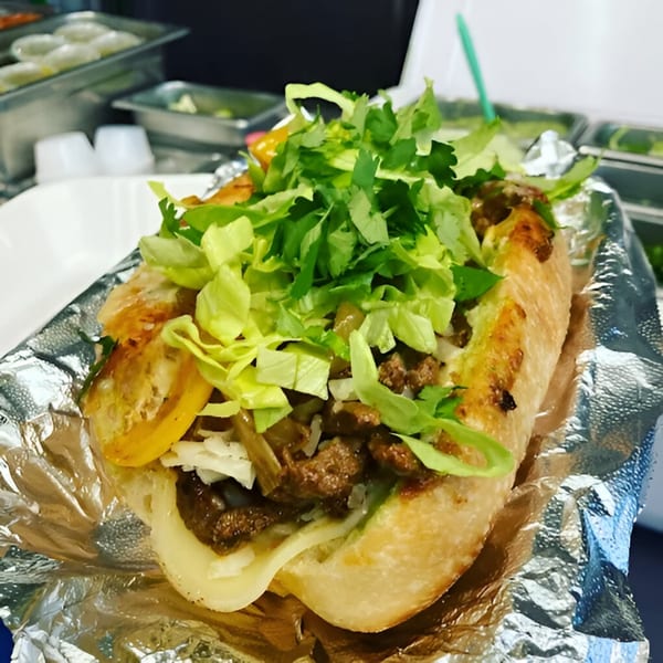 A Farmacy Cafe Mexican sandwich, overflowing with meat, cheese, lettuce, and cilantro, wrapped in foil.