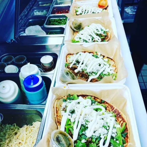 Several Farmacy Cafe sopes with meat, lettuce, cheese, and crema, ready for serving.