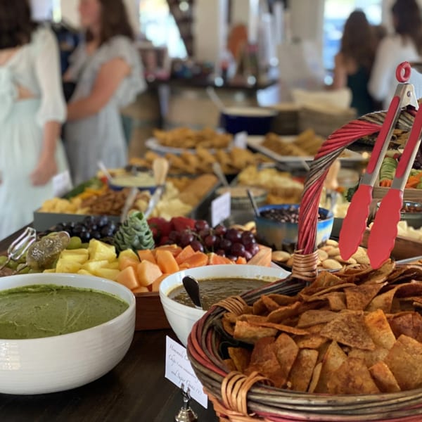 A buffet table with various Mexican dishes, including chips, dips, fruits, and other appetizers.
