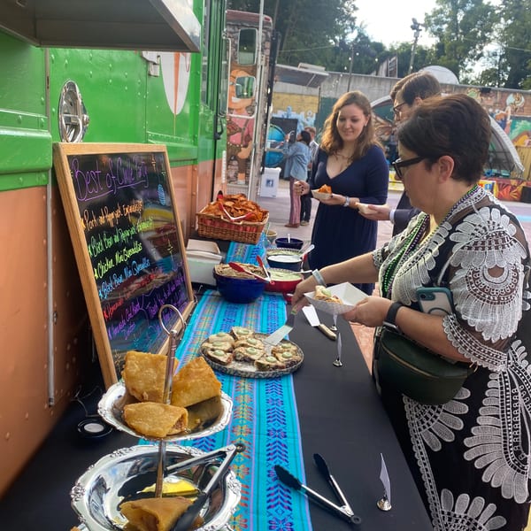 Guests at Farmacy Cafe's outdoor event selecting Mexican food from a buffet table.