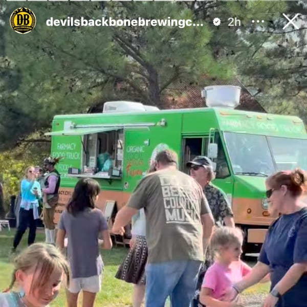 People gather around the Farmacy Cafe food truck, serving Mexican cuisine outdoors.
