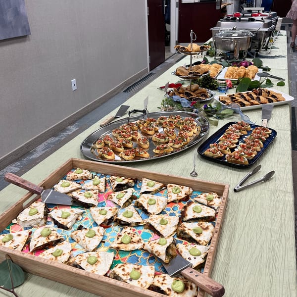 A buffet table laden with quesadillas, bruschetta, and other appetizers, with chafing dishes in the background.